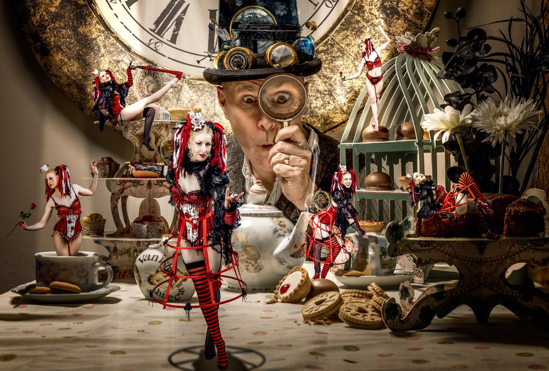 A whimsical burlesque take on Alice in Wonderland, featuring multiple miniature versions of a corseted Alice character in red and black, performing across a surreal tea party table. A curious man in a steampunk hat peers through a magnifying glass at the scene, surrounded by biscuits, teacups, and layered cakes. The theatrical setup is rich in fantasy detail, blending fairytale with vintage eccentricity.