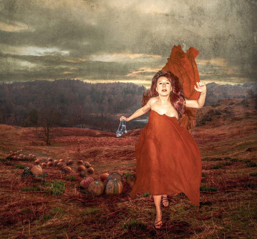 A woman in a flowing red gown runs barefoot through an autumnal field, clutching a single glass slipper. Her expression is urgent and determined, as oversized pumpkins trail behind her across the landscape. The scene is set beneath a dramatic sky at dusk, evoking a surreal reimagining of the Cinderella story with a bold, contemporary twist.