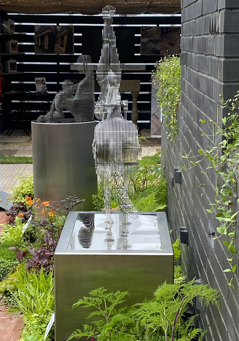 A stylised stainless steel sculpture by Tom Hiscox featuring a figure performing a handstand atop a horse, formed from layered steel contours and presented against a dark brick backdrop as part of a limited edition series.