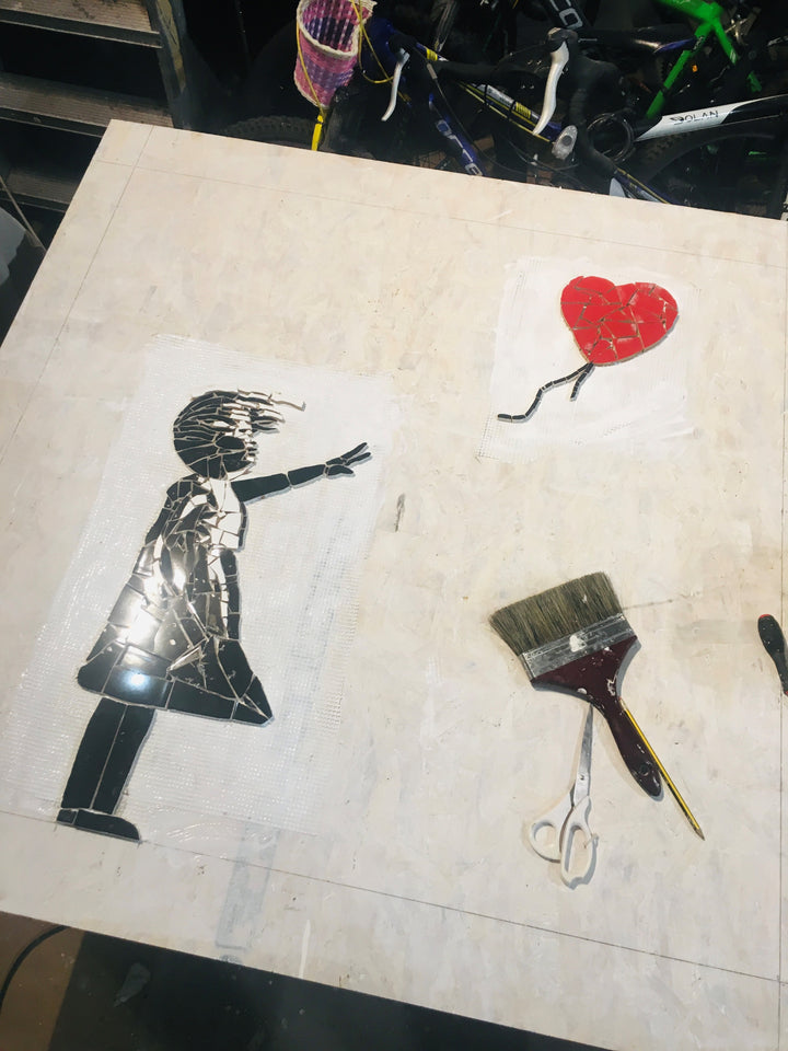 “Girl with Balloon” mosaic — a handcrafted ceramic tile artwork reimagining the iconic heart balloon image. Featuring black and white tiles with a vivid red heart, this bespoke commission blends street art symbolism with fine mosaic craftsmanship.