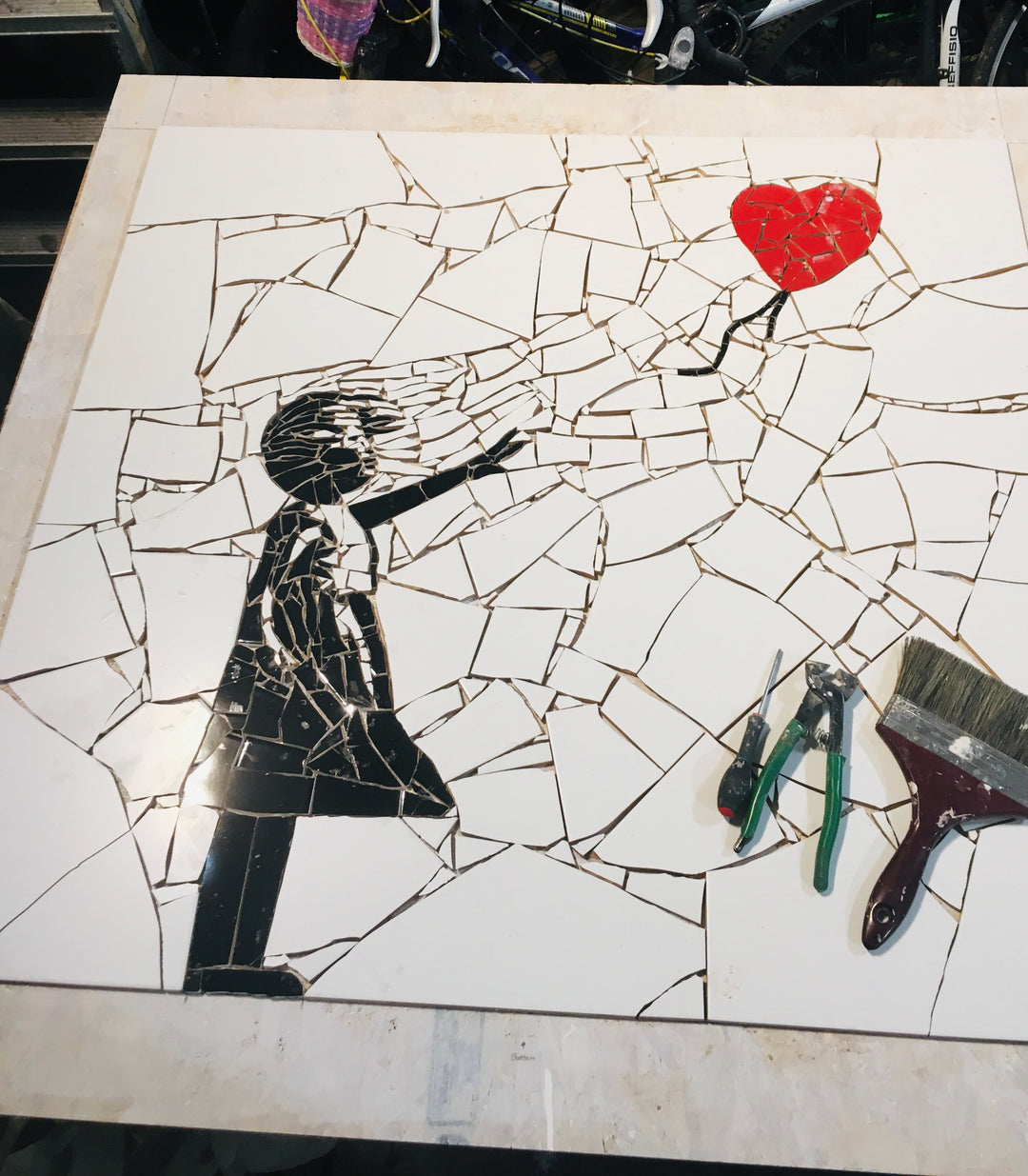 “Girl with Balloon” mosaic — a handcrafted ceramic tile artwork reimagining the iconic heart balloon image. Featuring black and white tiles with a vivid red heart, this bespoke commission blends street art symbolism with fine mosaic craftsmanship.