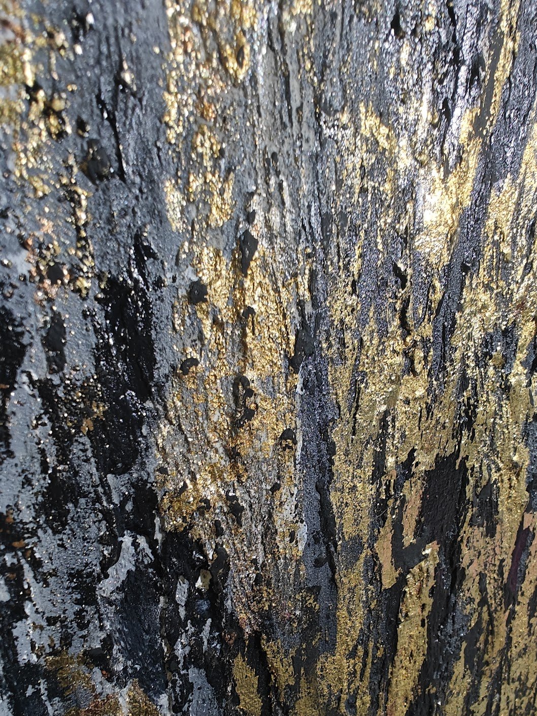 Textured abstract painting with vertical strokes in gold, black, and grey tones on a rough, layered surface