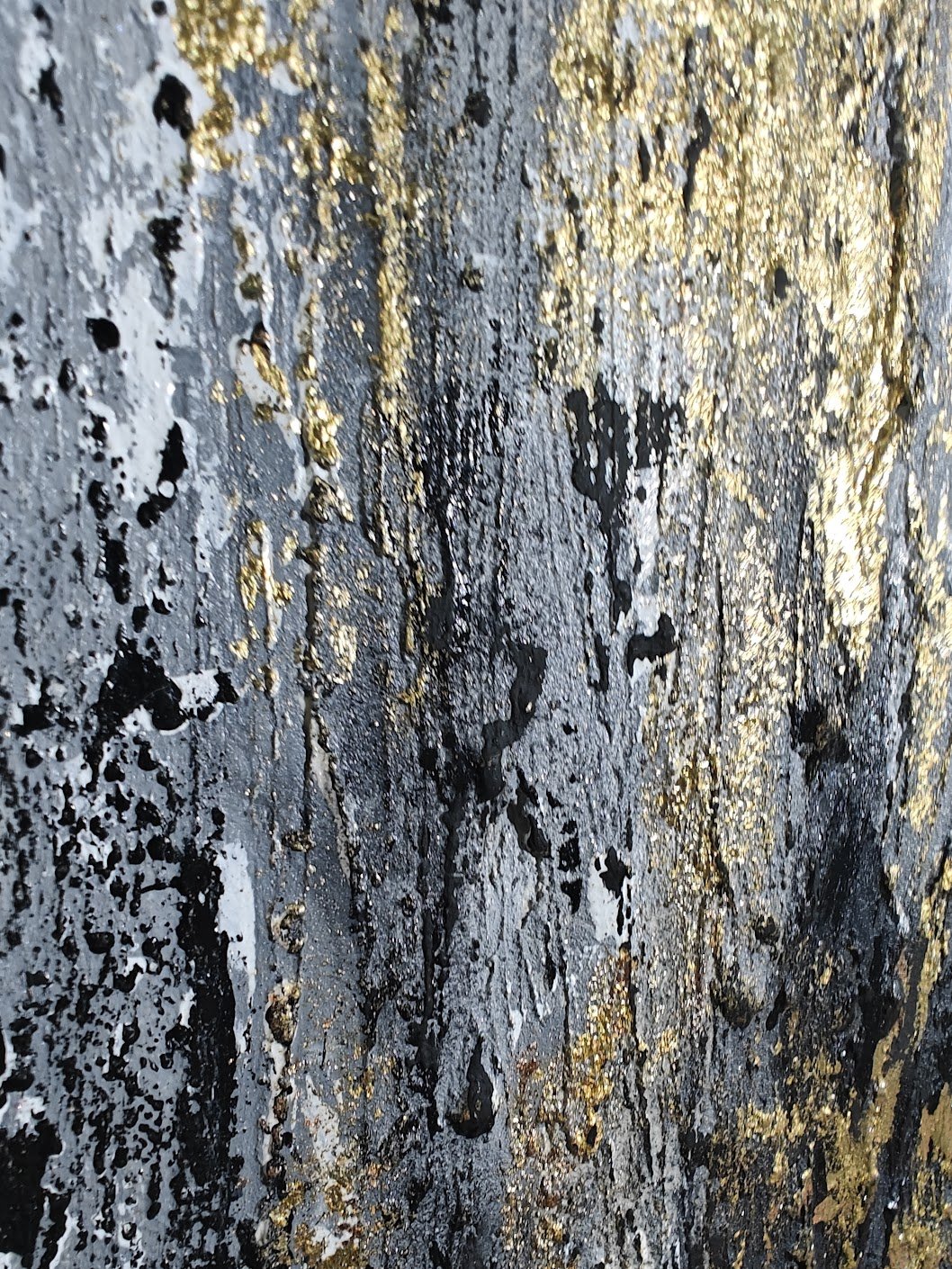 Textured abstract painting with vertical strokes in gold, black, and grey tones on a rough, layered surface