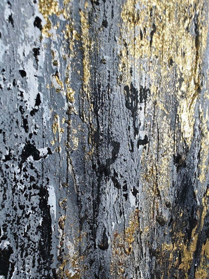 Textured abstract painting with vertical strokes in gold, black, and grey tones on a rough, layered surface