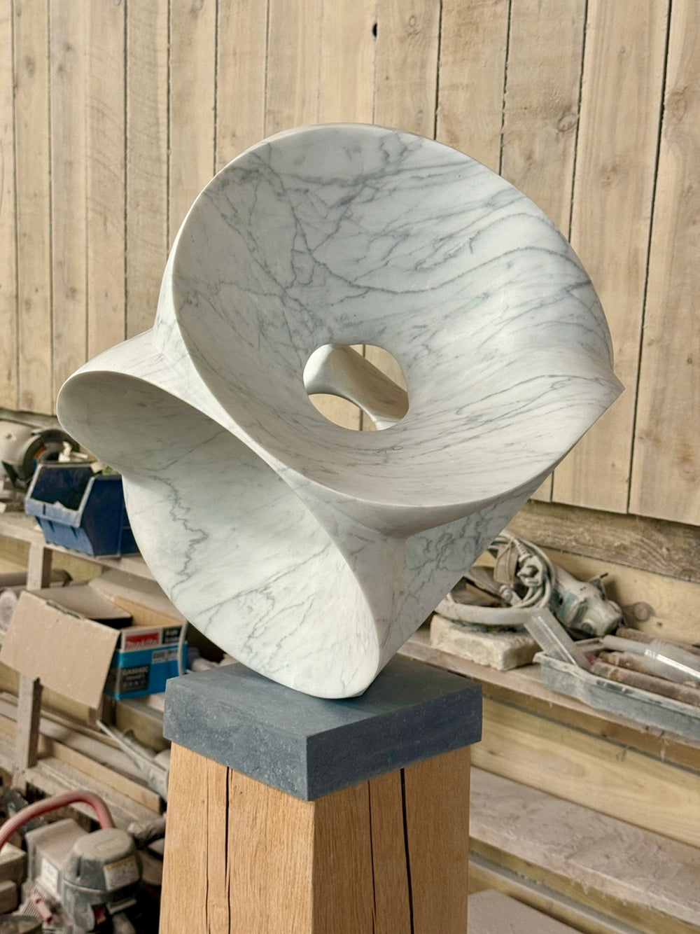 Abstract marble sculpture Good Vibrations V – 2025 by Hamish Holman, carved from Carrara marble with flowing organic curves and a central opening, featuring delicate grey veining on a smooth white surface, mounted on a stone and oak plinth.