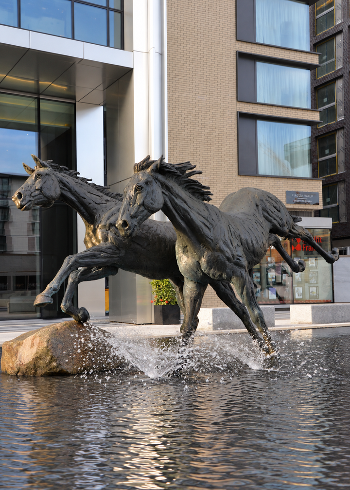 ‘Goodman's Horses Running Together’ by Hamish Mackie, a monumental limited-edition bronze sculpture depicting two powerful horses, a thoroughbred and a shire-cross, galloping together through water. Originally commissioned for Goodman's Fields in London, the dynamic public artwork captures muscular movement, flowing manes and the energy of horses in motion, finished in dark patinated bronze.