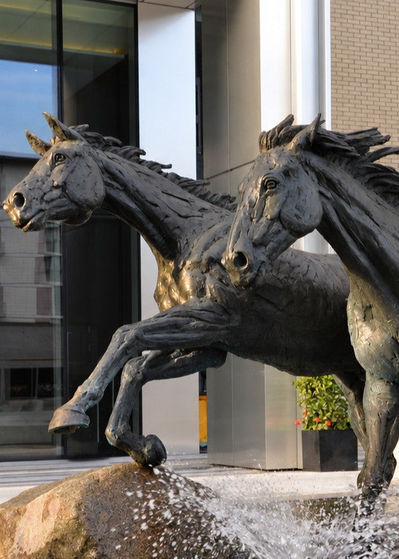 ‘Goodman's Horses Running Together’ by Hamish Mackie, a monumental limited-edition bronze sculpture depicting two powerful horses, a thoroughbred and a shire-cross, galloping together through water. Originally commissioned for Goodman's Fields in London, the dynamic public artwork captures muscular movement, flowing manes and the energy of horses in motion, finished in dark patinated bronze.