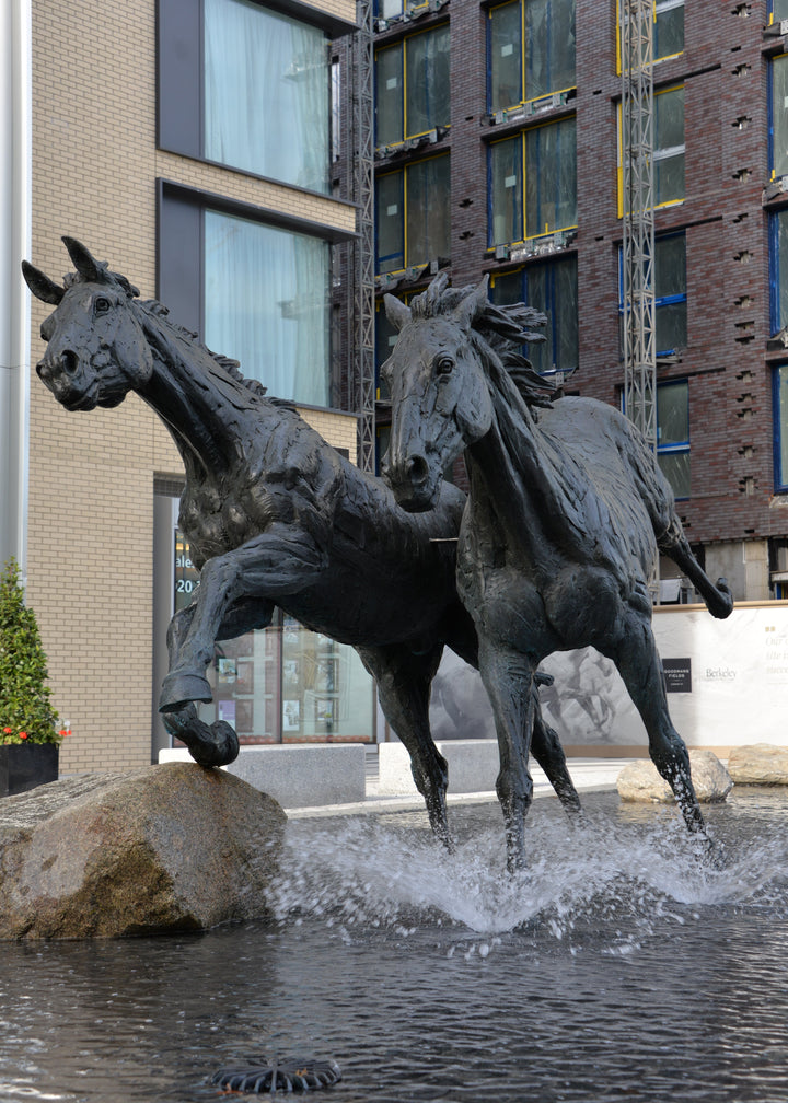 ‘Goodman's Horses Running Together’ by Hamish Mackie, a monumental limited-edition bronze sculpture depicting two powerful horses, a thoroughbred and a shire-cross, galloping together through water. Originally commissioned for Goodman's Fields in London, the dynamic public artwork captures muscular movement, flowing manes and the energy of horses in motion, finished in dark patinated bronze.