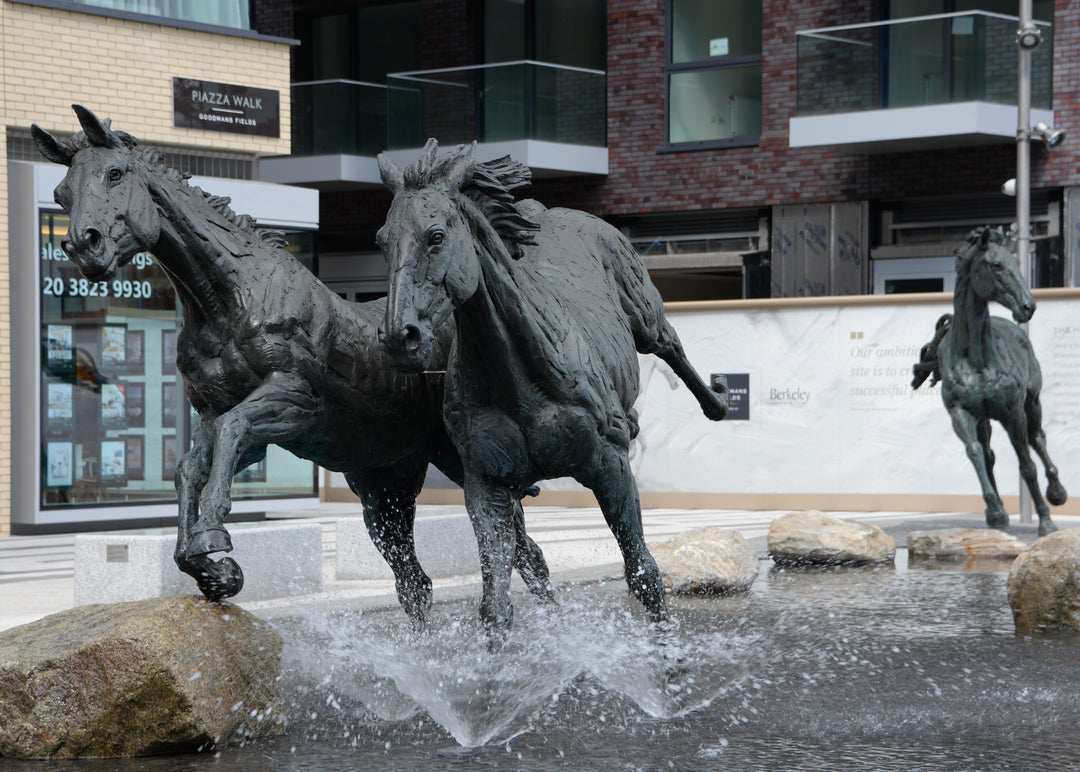 ‘Goodman's Horses Running Together’ by Hamish Mackie, a monumental limited-edition bronze sculpture depicting two powerful horses, a thoroughbred and a shire-cross, galloping together through water. Originally commissioned for Goodman's Fields in London, the dynamic public artwork captures muscular movement, flowing manes and the energy of horses in motion, finished in dark patinated bronze.