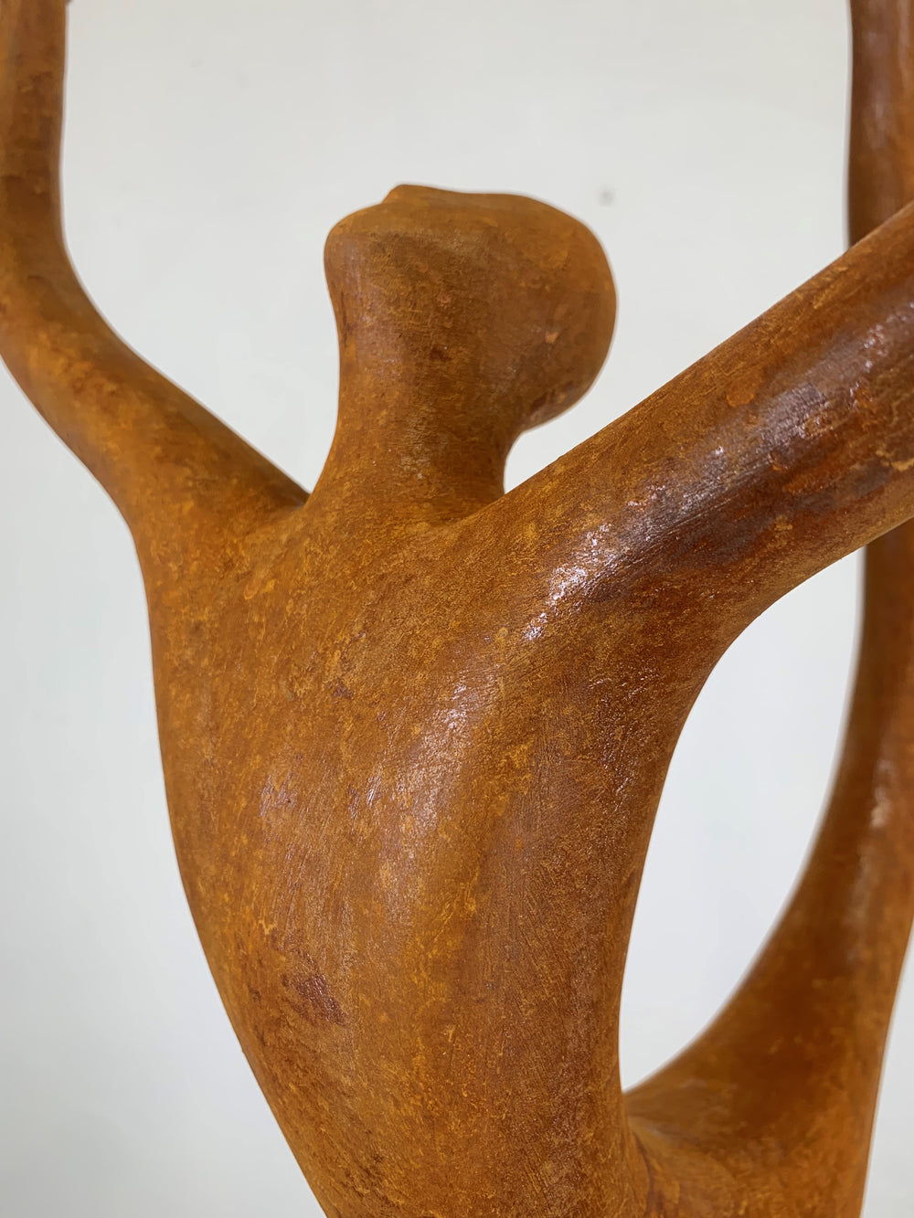 Rust-coloured bronze sculpture of an abstract dancer with elongated limbs, captured mid-pose in an energetic, gravity-defying stretch.