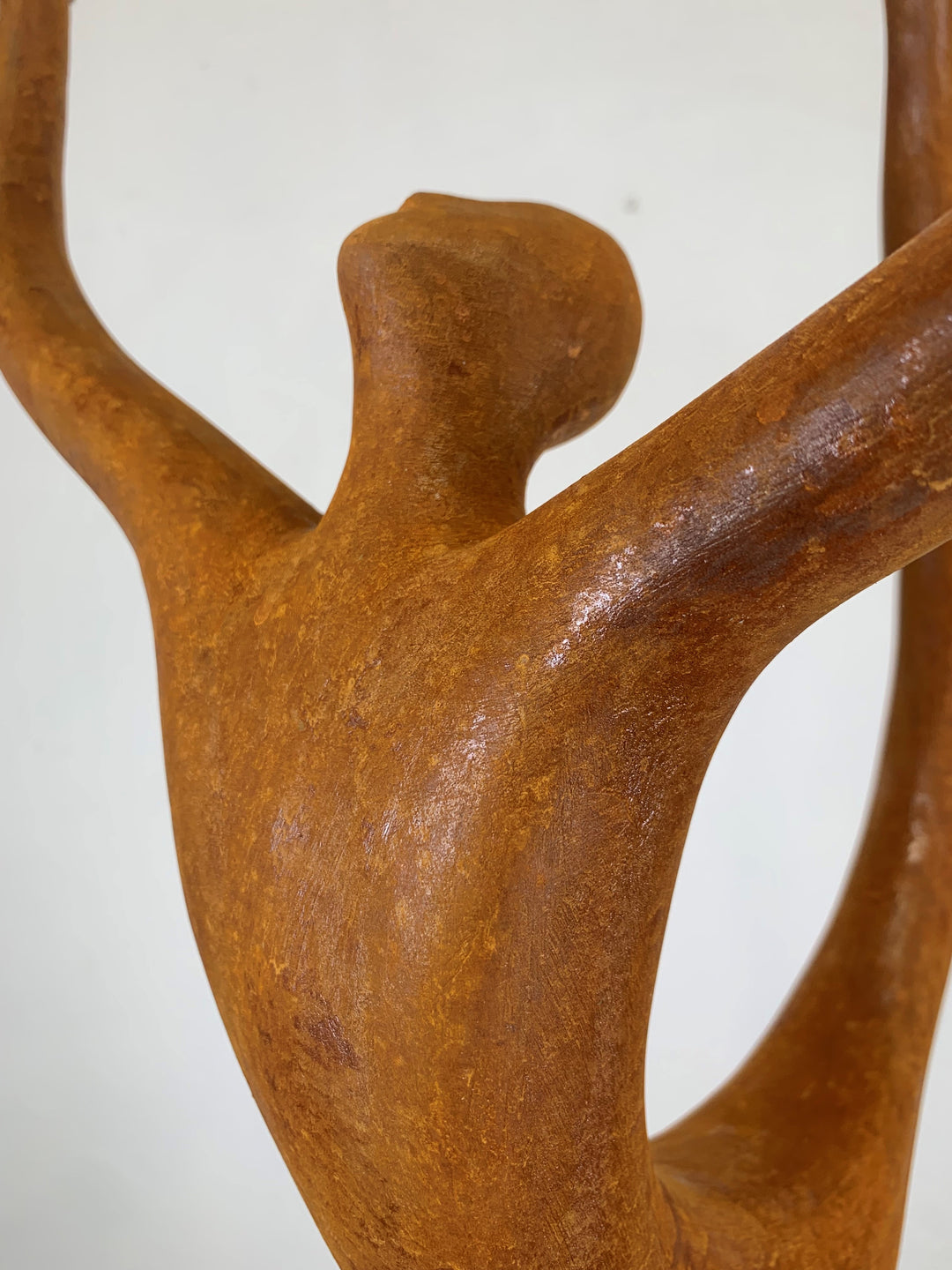 Rust-coloured bronze sculpture of an abstract dancer with elongated limbs, captured mid-pose in an energetic, gravity-defying stretch.