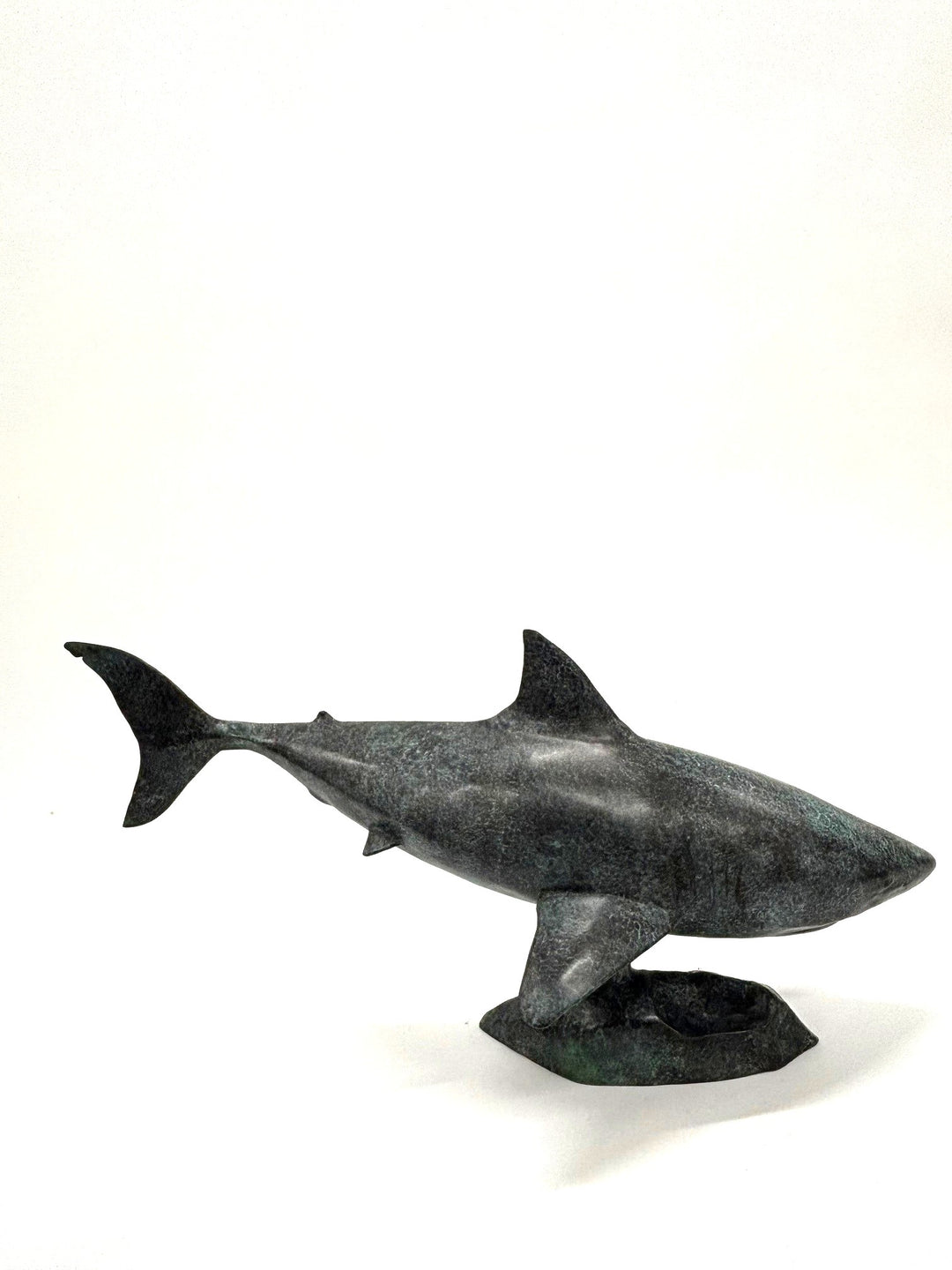 Bronze sculpture of a shark captured mid-motion, mounted on a textured base and finished in a deep mottled patina, cast as a limited edition artwork.