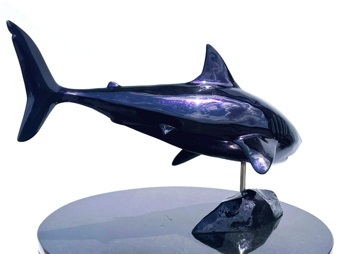 Sculpture titled Great White IV.2 (2025), depicting a stylised great white shark cast in deep blue Jesmonite with a high-gloss finish, mounted on a dark rock-like base.