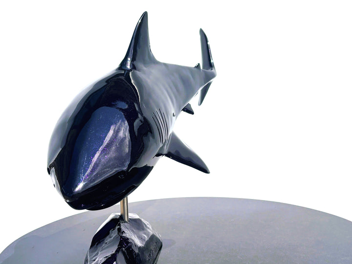 Sculpture titled Great White IV.2 (2025), depicting a stylised great white shark cast in deep blue Jesmonite with a high-gloss finish, mounted on a dark rock-like base.