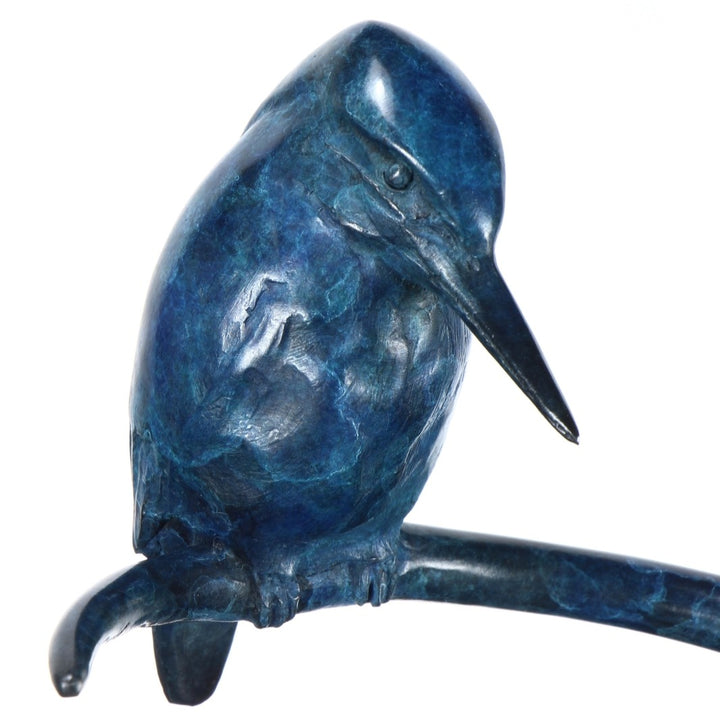 ‘Halcyon Days Maquette’ by Pat Bull, a limited-edition contemporary bronze wildlife sculpture depicting a kingfisher perched on a sweeping spiral bronze support, its head lowered and pointed beak angled towards the circular base below. The bird features finely detailed wing feathers and a smooth, rounded body finished in deep blue, navy and turquoise patina. The curved bronze stem and circular base share a mottled blue-green finish, creating a compact, elegant sculpture inspired by British wildlife.