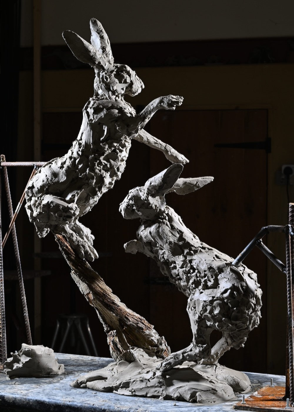 ‘Boxing Hares’ by Hamish Mackie, a limited-edition bronze wildlife sculpture depicting two hares leaping and boxing in mid-air during their characteristic springtime courtship behaviour. The dynamic composition captures their extended limbs, twisting bodies and expressive movement, with richly textured surfaces that convey the energy of the original hand-modelled clay. Photograph shows the original clay sculpture prior to bronze casting.