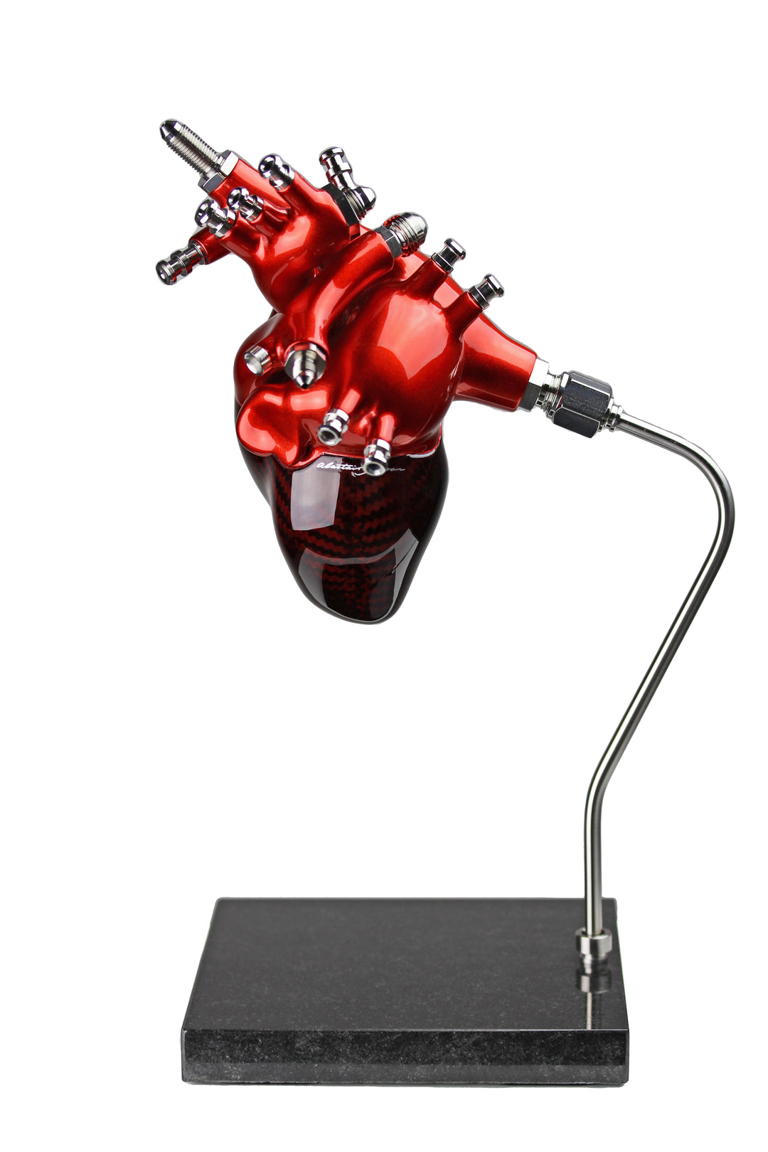 A vivid heart sculpture by Alastair Gibson, crafted from red-tinted 2x2 twill carbon fibre and finished with 3D-printed ABS atriums. Featuring titanium fuel and hydraulic fittings from Grand Prix cars, it fuses organic form with motorsport engineering. Finished in deep racing red with a UV-resistant gloss, it’s desk-mounted on a polished granite base with a stainless steel hydraulic support—blending precision with striking visual impact.