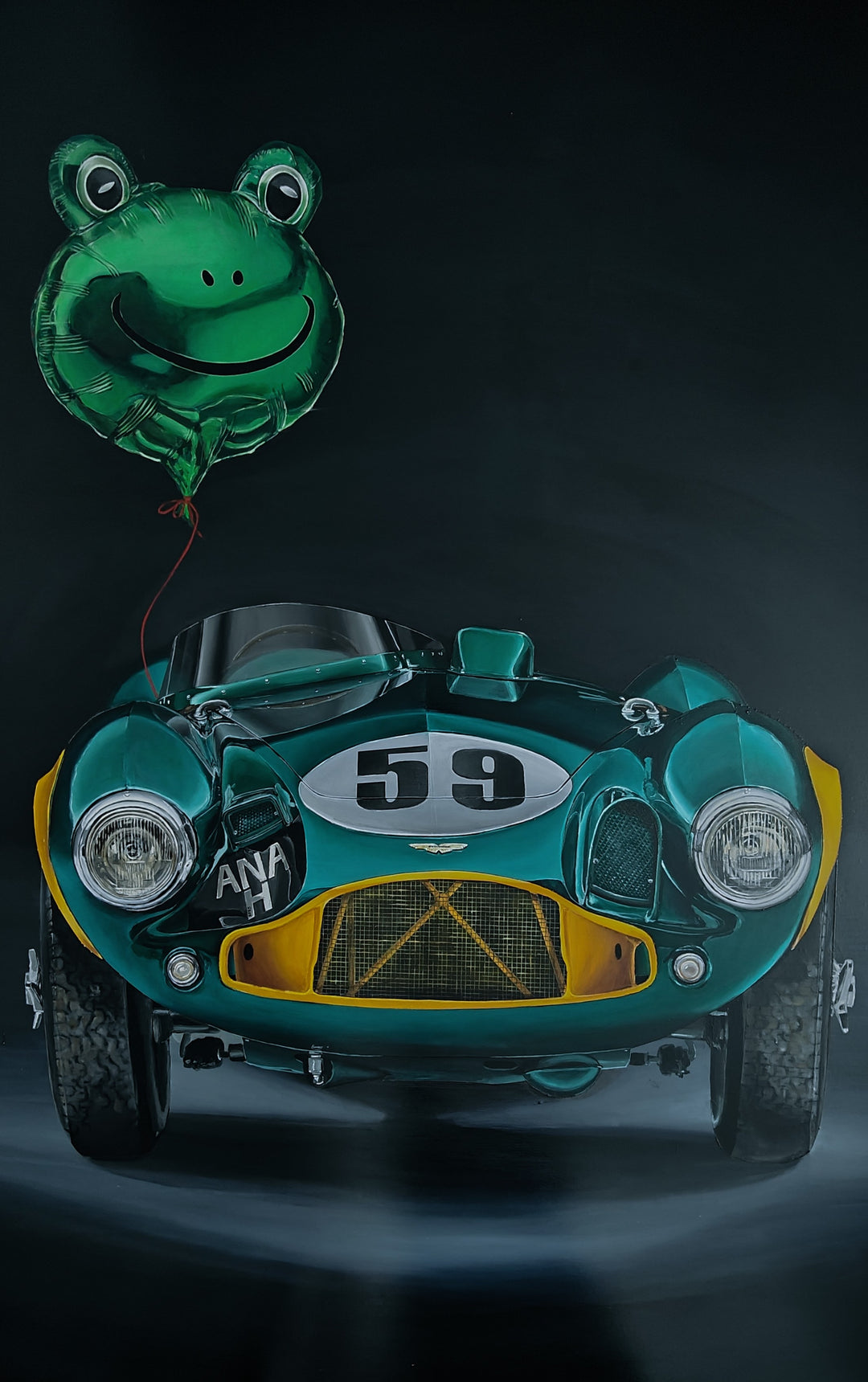 Hyper-realistic painting of a classic British racing green Aston Martin DB3S front-on against a deep black background, with a shiny metallic green frog-shaped balloon floating above the car, its red string tied to the vehicle — a playful contrast of automotive heritage and childlike whimsy.