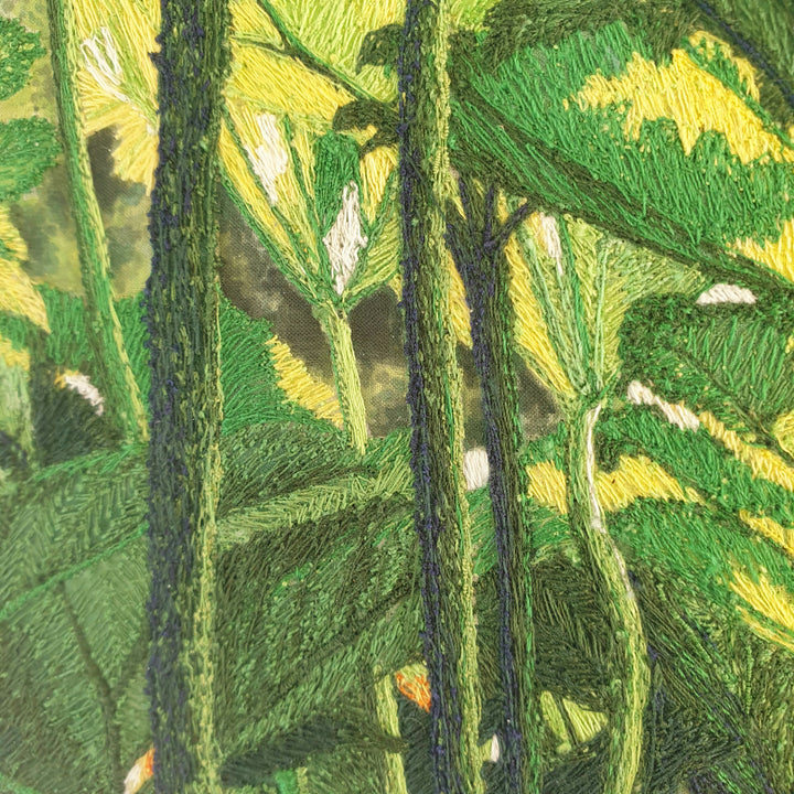 Dense embroidered scene of tropical foliage with overlapping green and yellow leaves viewed from beneath a lush canopy.
