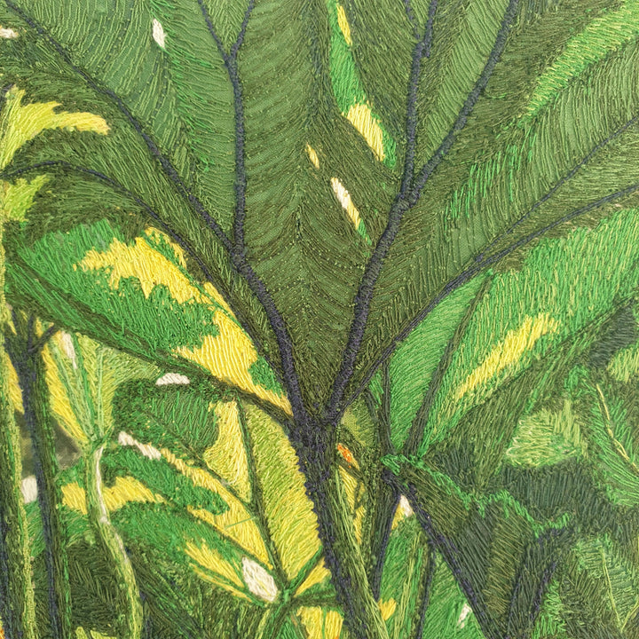 Dense embroidered scene of tropical foliage with overlapping green and yellow leaves viewed from beneath a lush canopy.
