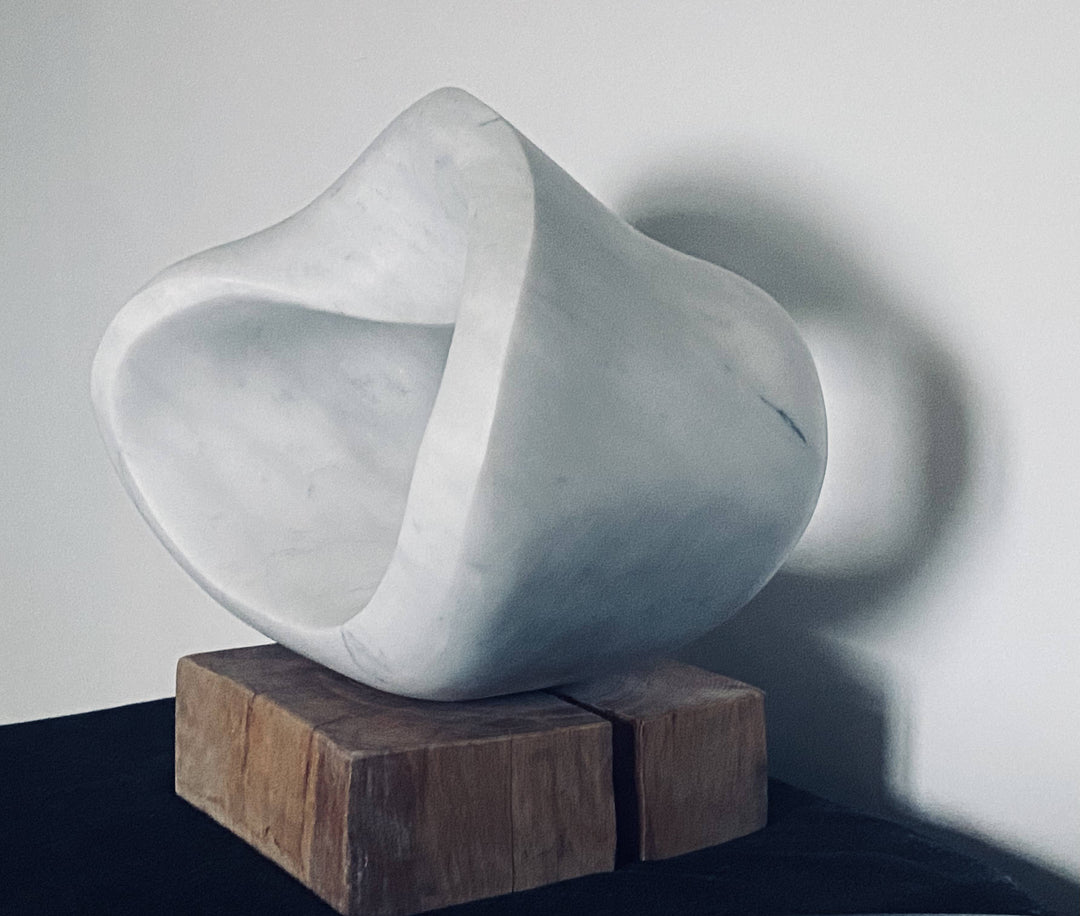 Abstract sculpture Hula by Brendan Cullen, hand-carved from smooth white Carrara marble with soft grey veining, organic flowing form suggesting movement and balance, mounted on a rustic wooden base.