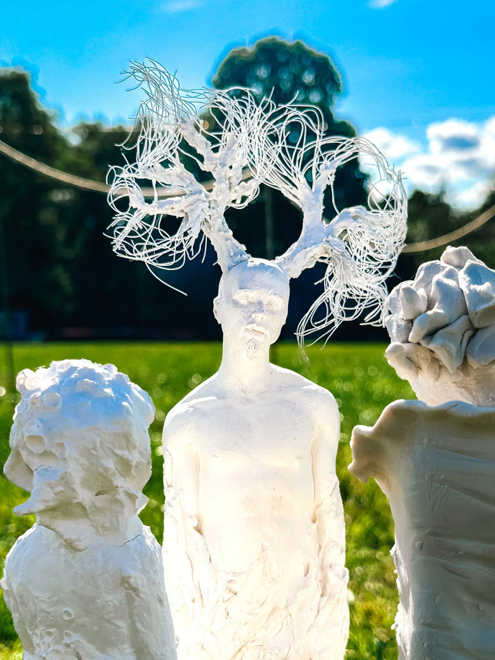 Eve Shepherd Children of Nature sculptural installation featuring around 100 individual porcelain hybrid figures combining human, animal, plant and fungal forms, arranged in a large illuminated fairy ring surrounded by natural moss.