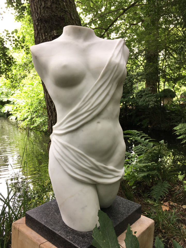 Lucy Unwin marble sculpture Venus, hand carved from white Statuary Carrara marble, depicting a contemporary female torso partially wrapped in flowing carved drapery with smooth figurative contours and finely detailed folds.