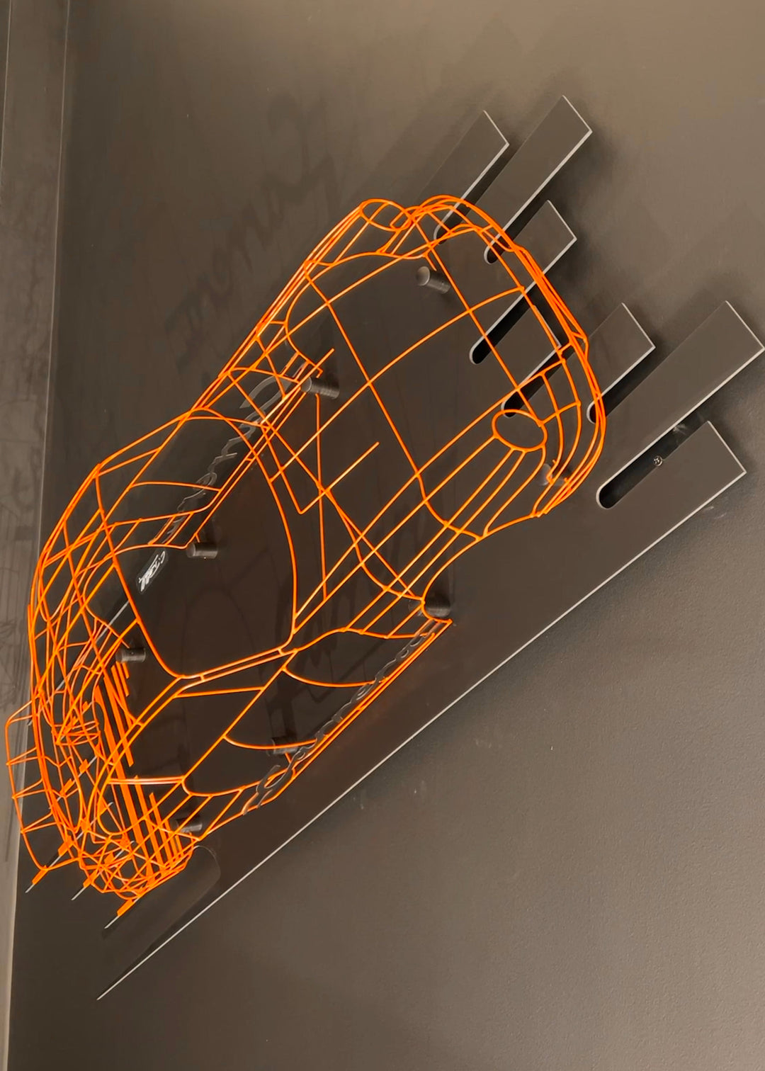 Handcrafted Porsche 911 2.7 RS wire sculpture by Chris Twitchell, finished in vivid Tangerine orange with black Carrera script. This detailed artwork captures the iconic pre-impact bumper 911 form — from its classic round headlights to the signature ducktail spoiler — reimagined as a precision-engineered wireframe sculpture that celebrates Porsche’s timeless design and performance heritage.
