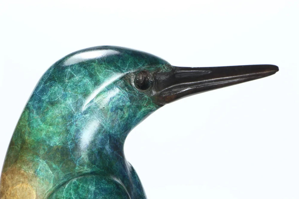 Elegant bronze sculpture of a stylised kingfisher perched on a tall, curved base. The bird features a vivid patina in shades of emerald green and turquoise, with a rich brown lower half and dark bronze beak, all finished with a lustrous polish.