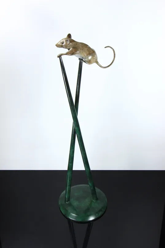 Bronze sculpture of a curious mouse perched high atop two crossed stilts, tail arched playfully behind, poised in a moment of bold exploration and balance.