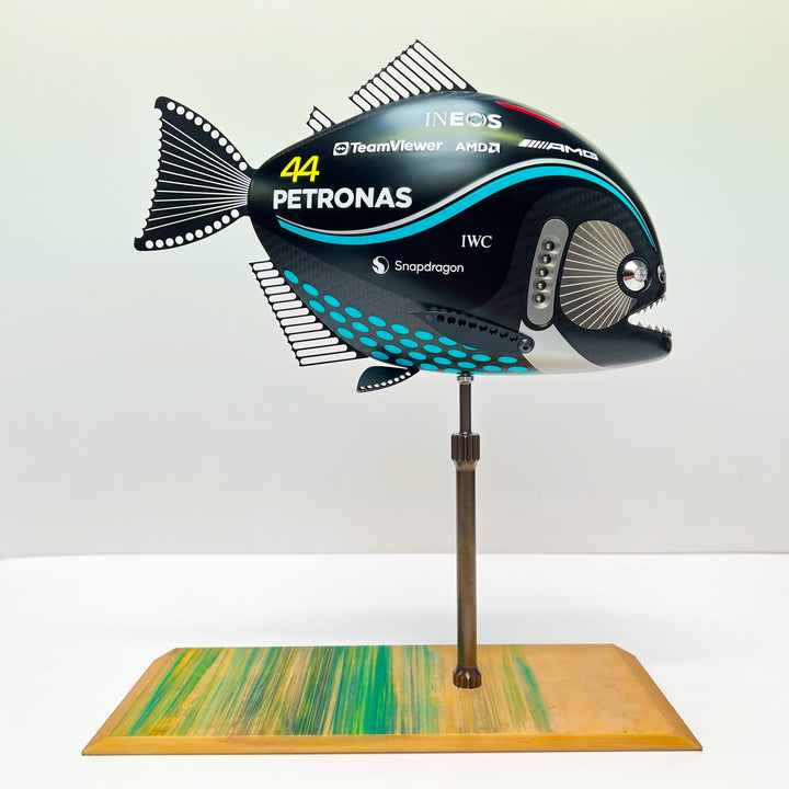 Close-up views of Predator in Motion – a sculptural fusion of engineering and marine form by Alastair Gibson. The body is formed from layered carbon fibre with a matte black finish and turquoise vinyl livery inspired by Lewis Hamilton’s 2023 Mercedes AMG Formula One car. Sponsor graphics include Petronas, Ineos, AMD, and TeamViewer. Satin black stainless steel fins and titanium teeth reflect precision F1 detailing. Polished titanium eyes are inset with a pink diamond-effect crystal. Mounted on a torsion bar
