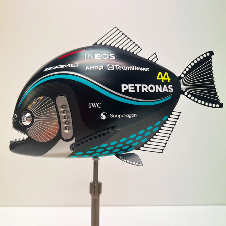 Close-up views of Predator in Motion – a sculptural fusion of engineering and marine form by Alastair Gibson. The body is formed from layered carbon fibre with a matte black finish and turquoise vinyl livery inspired by Lewis Hamilton’s 2023 Mercedes AMG Formula One car. Sponsor graphics include Petronas, Ineos, AMD, and TeamViewer. Satin black stainless steel fins and titanium teeth reflect precision F1 detailing. Polished titanium eyes are inset with a pink diamond-effect crystal. Mounted on a torsion bar