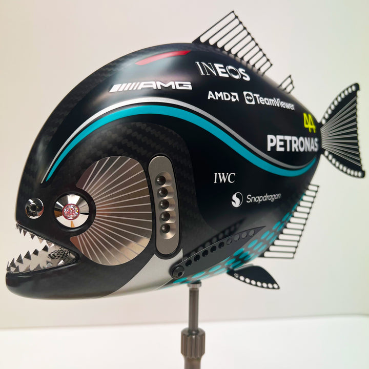Close-up views of Predator in Motion – a sculptural fusion of engineering and marine form by Alastair Gibson. The body is formed from layered carbon fibre with a matte black finish and turquoise vinyl livery inspired by Lewis Hamilton’s 2023 Mercedes AMG Formula One car. Sponsor graphics include Petronas, Ineos, AMD, and TeamViewer. Satin black stainless steel fins and titanium teeth reflect precision F1 detailing. Polished titanium eyes are inset with a pink diamond-effect crystal. Mounted on a torsion bar