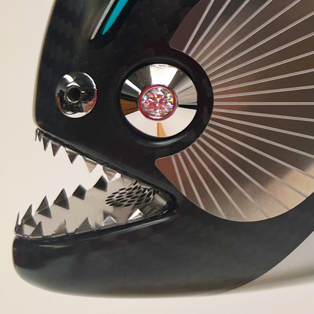 Close-up views of Predator in Motion – a sculptural fusion of engineering and marine form by Alastair Gibson. The body is formed from layered carbon fibre with a matte black finish and turquoise vinyl livery inspired by Lewis Hamilton’s 2023 Mercedes AMG Formula One car. Sponsor graphics include Petronas, Ineos, AMD, and TeamViewer. Satin black stainless steel fins and titanium teeth reflect precision F1 detailing. Polished titanium eyes are inset with a pink diamond-effect crystal. Mounted on a torsion bar