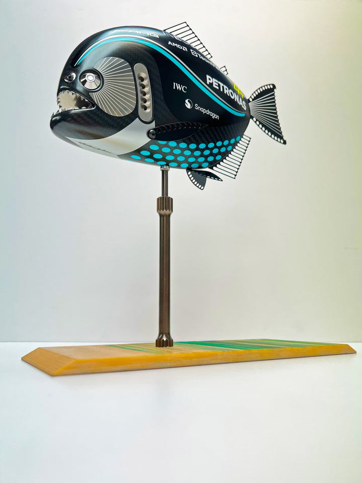 Close-up views of Predator in Motion – a sculptural fusion of engineering and marine form by Alastair Gibson. The body is formed from layered carbon fibre with a matte black finish and turquoise vinyl livery inspired by Lewis Hamilton’s 2023 Mercedes AMG Formula One car. Sponsor graphics include Petronas, Ineos, AMD, and TeamViewer. Satin black stainless steel fins and titanium teeth reflect precision F1 detailing. Polished titanium eyes are inset with a pink diamond-effect crystal. Mounted on a torsion bar