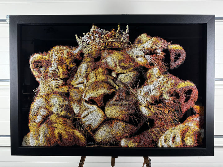 A richly textured injected-scribble artwork depicting a majestic lion wearing a crown, resting peacefully with three lion cubs nestled against him. The composition glows with warm tones of gold, amber, orange and cream, set against a deep black background that enhances the dimensional, thread-like detailing.