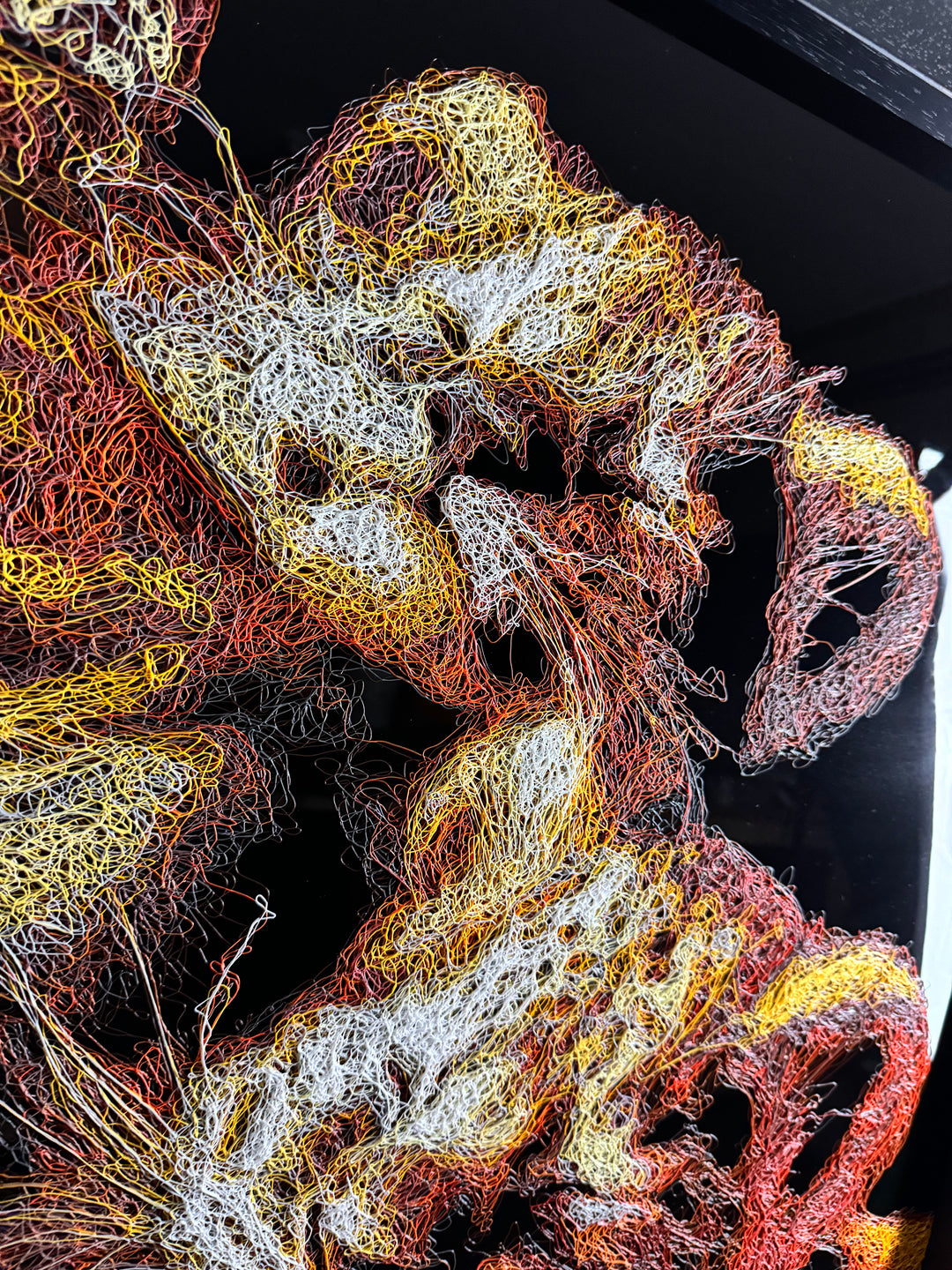 A richly textured injected-scribble artwork depicting a majestic lion wearing a crown, resting peacefully with three lion cubs nestled against him. The composition glows with warm tones of gold, amber, orange and cream, set against a deep black background that enhances the dimensional, thread-like detailing.