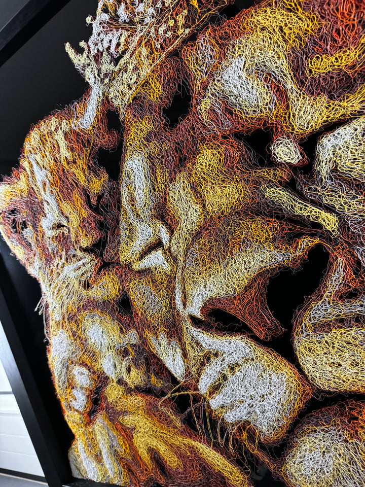 A richly textured injected-scribble artwork depicting a majestic lion wearing a crown, resting peacefully with three lion cubs nestled against him. The composition glows with warm tones of gold, amber, orange and cream, set against a deep black background that enhances the dimensional, thread-like detailing.