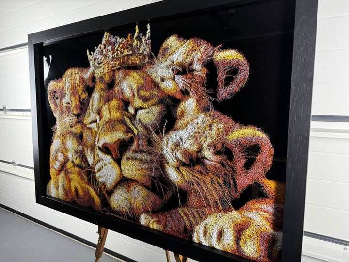 A richly textured injected-scribble artwork depicting a majestic lion wearing a crown, resting peacefully with three lion cubs nestled against him. The composition glows with warm tones of gold, amber, orange and cream, set against a deep black background that enhances the dimensional, thread-like detailing.
