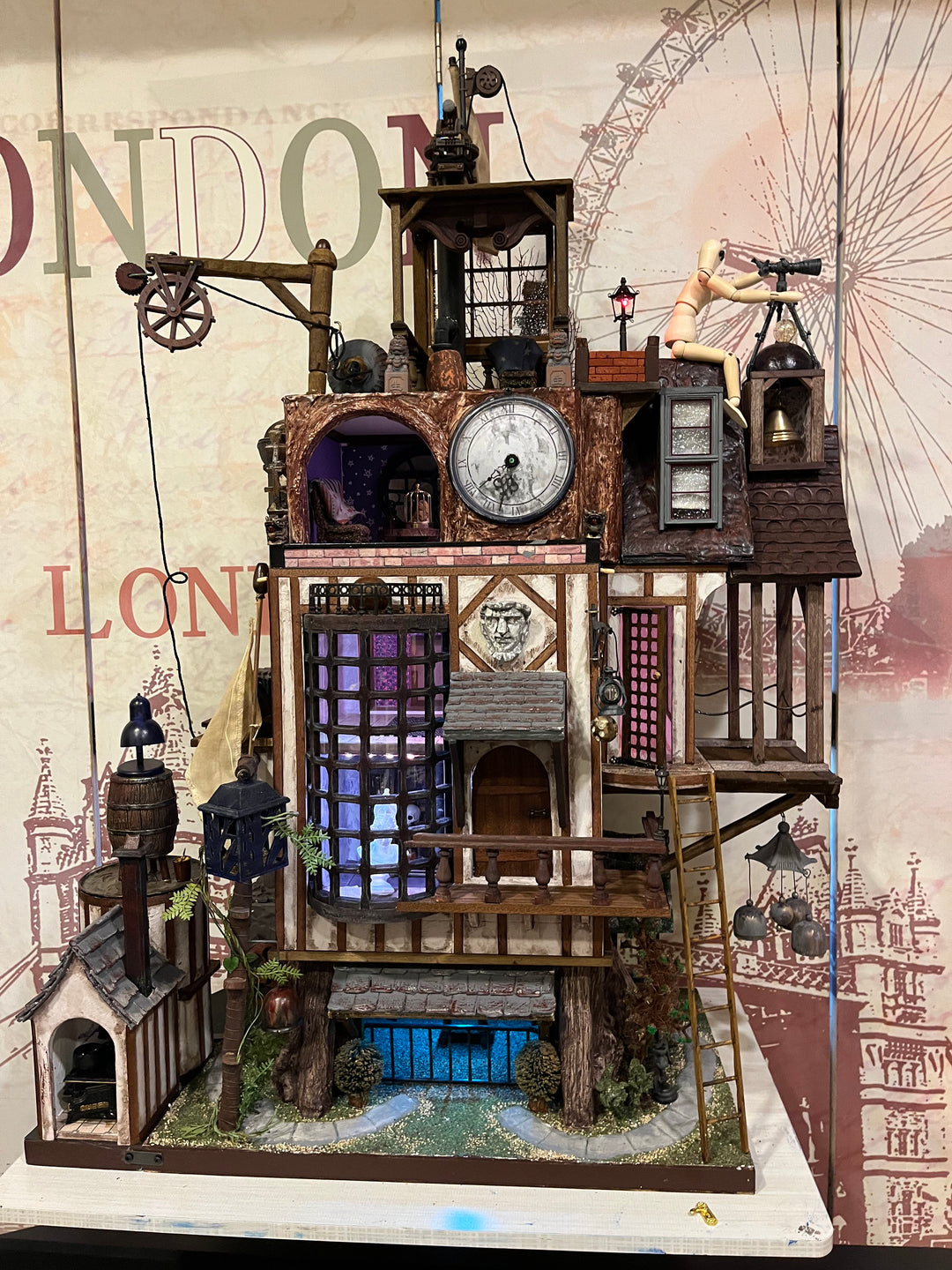 Illuminated steampunk-style dolls house with gears, dials, glowing purple windows, and intricate handcrafted architectural details.