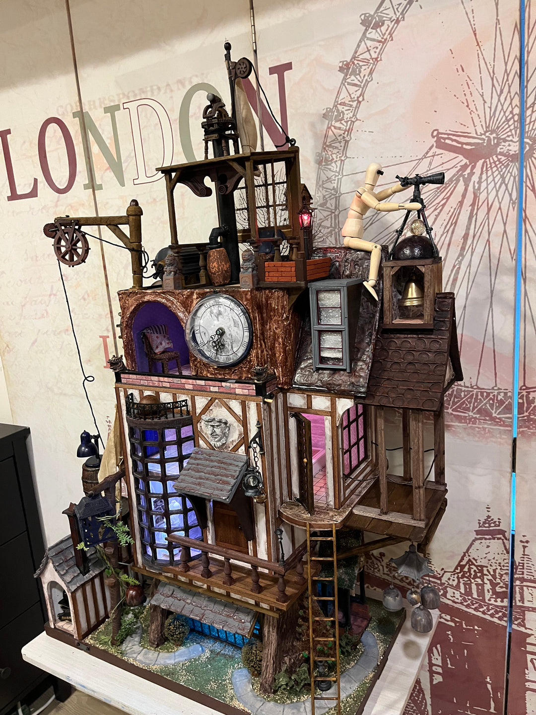 Illuminated steampunk-style dolls house with gears, dials, glowing purple windows, and intricate handcrafted architectural details.