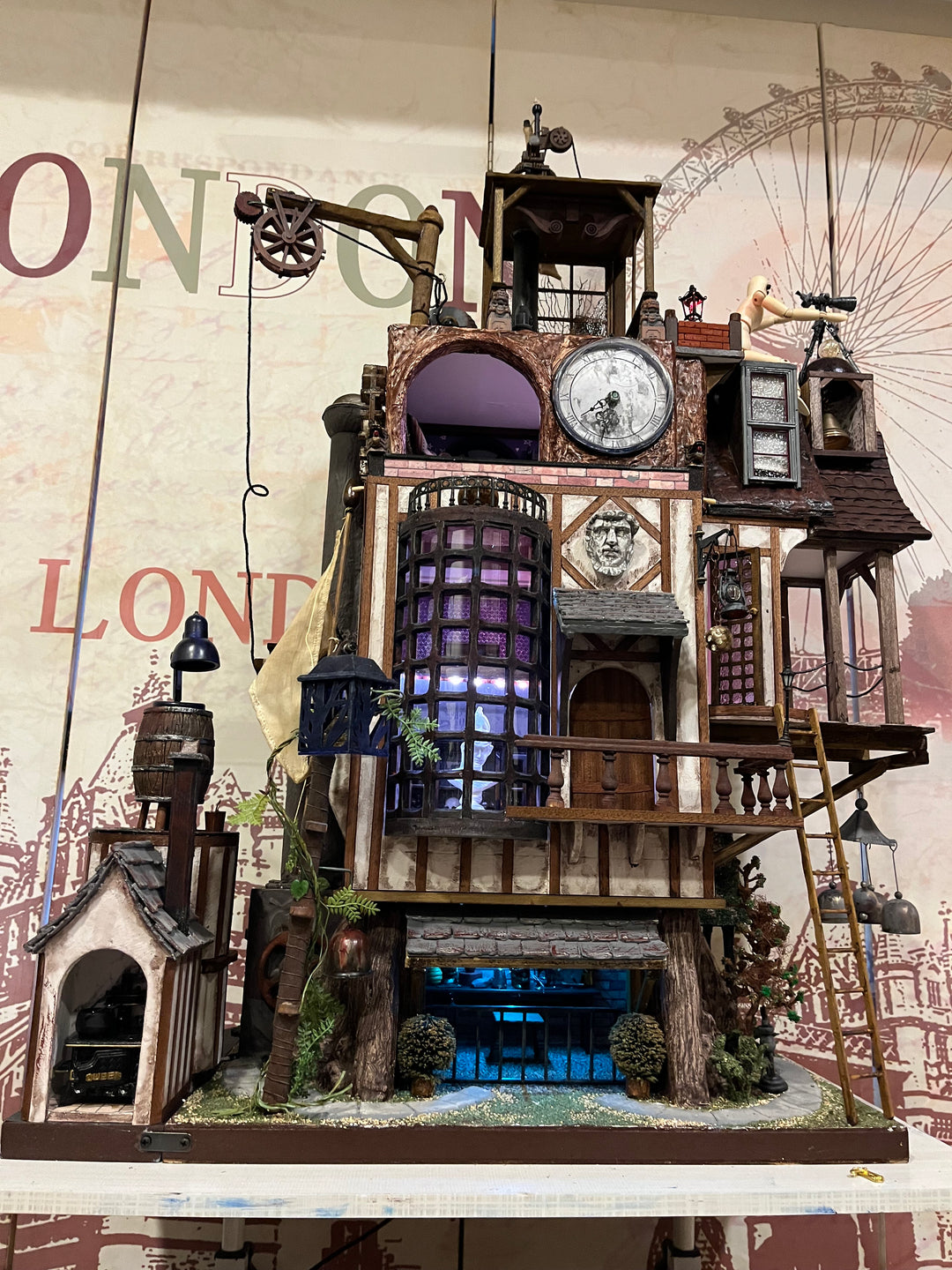Illuminated steampunk-style dolls house with gears, dials, glowing purple windows, and intricate handcrafted architectural details.