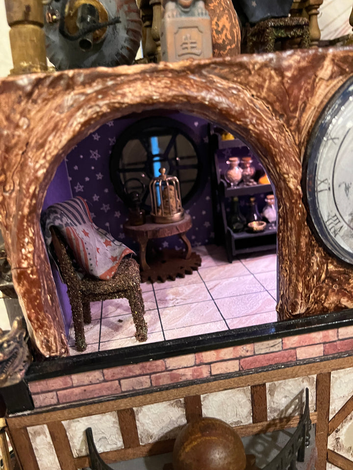 Illuminated steampunk-style dolls house with gears, dials, glowing purple windows, and intricate handcrafted architectural details.
