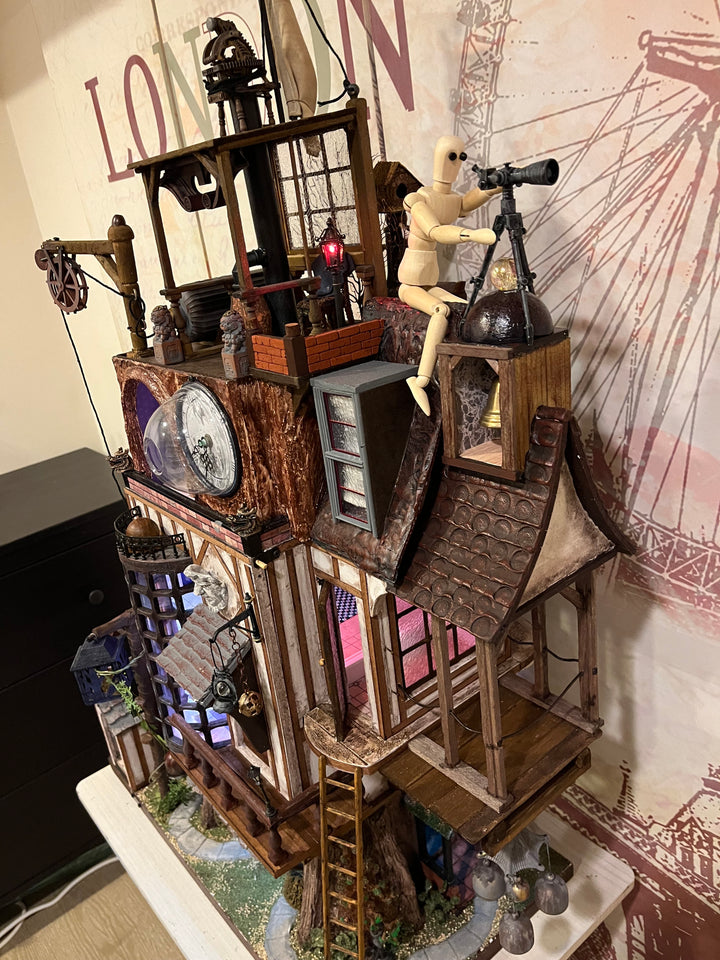 Illuminated steampunk-style dolls house with gears, dials, glowing purple windows, and intricate handcrafted architectural details.