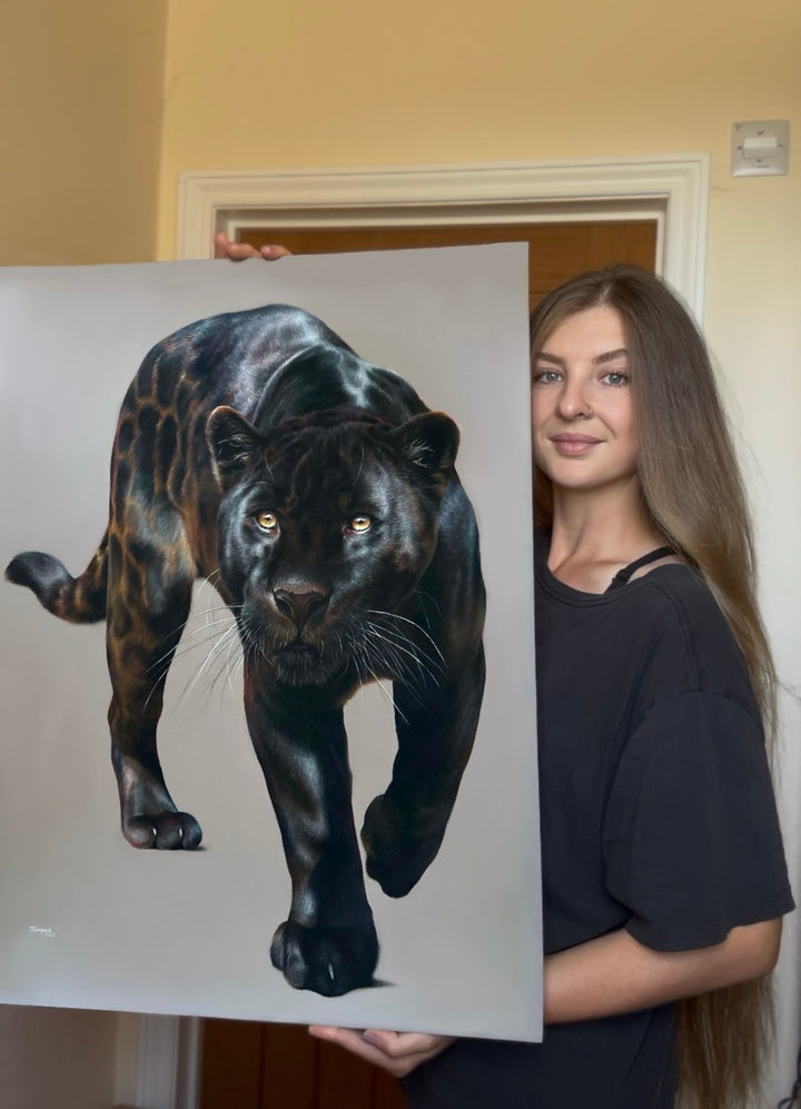 Jemma Worsfold’s Silent Shadow, hyper-real coloured pencil portrait of Neron the melanistic jaguar, golden eyes fixed ahead, sleek black coat with bronze-brown ghost rosettes, on dark grey pastelmat, capturing power, elegance, and predatory grace.