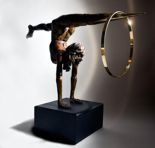 Teresa Wells’ Viktoriya (2018), limited edition bronze and brass sculpture on granite, portraying a powerful female acrobat in a one-armed handstand with legs extended horizontally, one foot tapering into a polished brass point that pierces a large brass hoop. The patinated bronze figure features finely modelled musculature, braided hair, and a dynamic forward gaze, balancing strength and grace. Mounted on a solid black granite base, the 100cm×30cm×50cm, 73kg piece is designed for impactful indoor display.