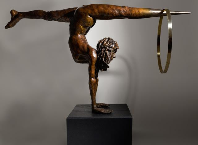 Teresa Wells’ Viktoriya (2018), limited edition bronze and brass sculpture on granite, portraying a powerful female acrobat in a one-armed handstand with legs extended horizontally, one foot tapering into a polished brass point that pierces a large brass hoop. The patinated bronze figure features finely modelled musculature, braided hair, and a dynamic forward gaze, balancing strength and grace. Mounted on a solid black granite base, the 100cm×30cm×50cm, 73kg piece is designed for impactful indoor display.