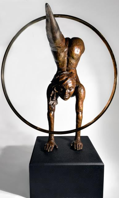Teresa Wells’ Viktoriya (2018), limited edition bronze and brass sculpture on granite, portraying a powerful female acrobat in a one-armed handstand with legs extended horizontally, one foot tapering into a polished brass point that pierces a large brass hoop. The patinated bronze figure features finely modelled musculature, braided hair, and a dynamic forward gaze, balancing strength and grace. Mounted on a solid black granite base, the 100cm×30cm×50cm, 73kg piece is designed for impactful indoor display.