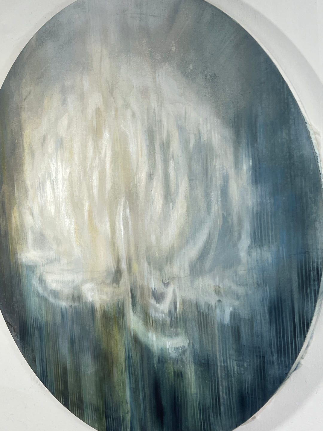 Circular abstract painting of a pale lotus-like bloom on silk and paper in cool grey-blue tones.