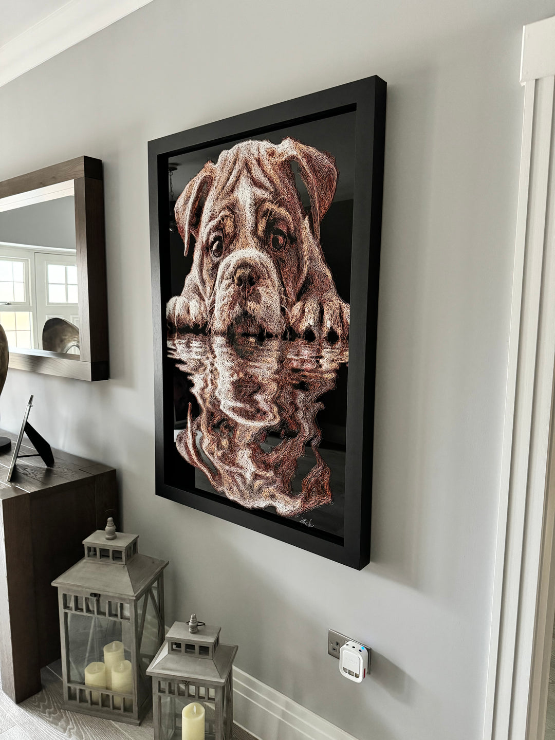 Vibrant injected-scribble artwork of a bulldog puppy resting at the edge of rippling water, its reflection distorted in swirling tones of white, tan, copper and brown, with dense textured linework creating a three-dimensional, energetic surface.